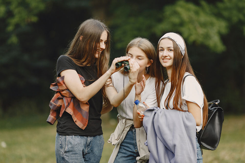 teenage girls on school trip looking through binoculars